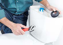 Photograph of plumbers installing parts in a toilet tank repair