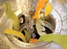 Photograph of kitchen scraps being washed into an in-sink garbage disposal